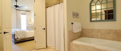 A bathroom with a bathtub, a shower curtain, and a mirror.