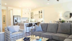 A modern living room with a grey sofa, patterned armchair, and a glass coffee table. - The Sadie, 3BR Townhome by VelvetDitchVillas (Oxford)