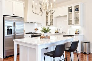 A modern kitchen with a central island, stainless steel appliances, and a chandelier. - The Sadie, Walk to Campus, by Velvet Ditch Villas (Oxford)