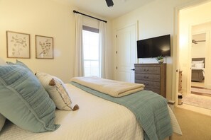 A bedroom with a bed, a flat-screen TV, a dresser, and a window with curtains. - The Sadie, Walk to Campus, by Velvet Ditch Villas (Oxford)