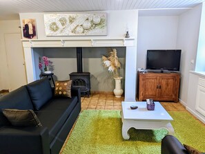 A living room with a black sofa, a white coffee table, a TV on a wooden cabinet, a fireplace, and a decorative wall piece.