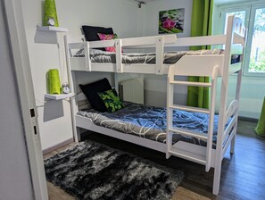 A bunk bed with a shelf above, a small clock, and a picture on the wall.