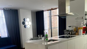 Una cocina moderna con una isla central, estufa integrada y un amplio ventanal con cortinas.
