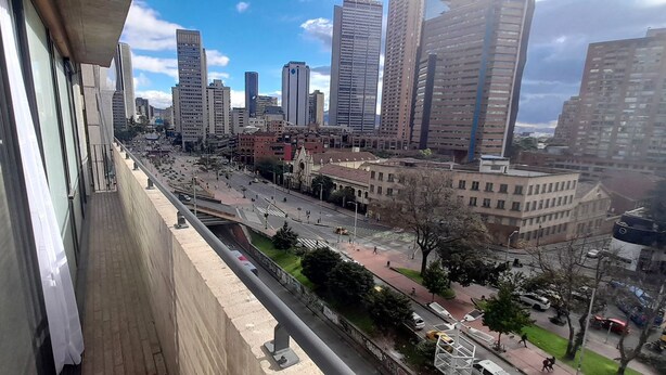 Un paisaje urbano con edificios altos, una calle concurrida y un paso de peatones.