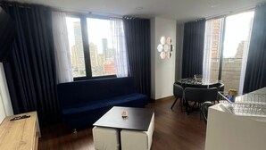 Una sala de estar moderna con un sofá azul, una mesita blanca y un comedor con sillas.