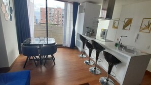 Una cocina moderna con comedor, una barra y vistas a edificios a través del ventanal.