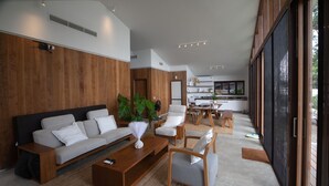 Ein modernes Wohnzimmer mit einer Couch, Sesseln, einem Couchtisch und einem Essbereich mit Tisch und Stühlen.