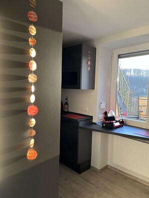 A modern kitchen with a black countertop, a wine bottle, and a red mat.