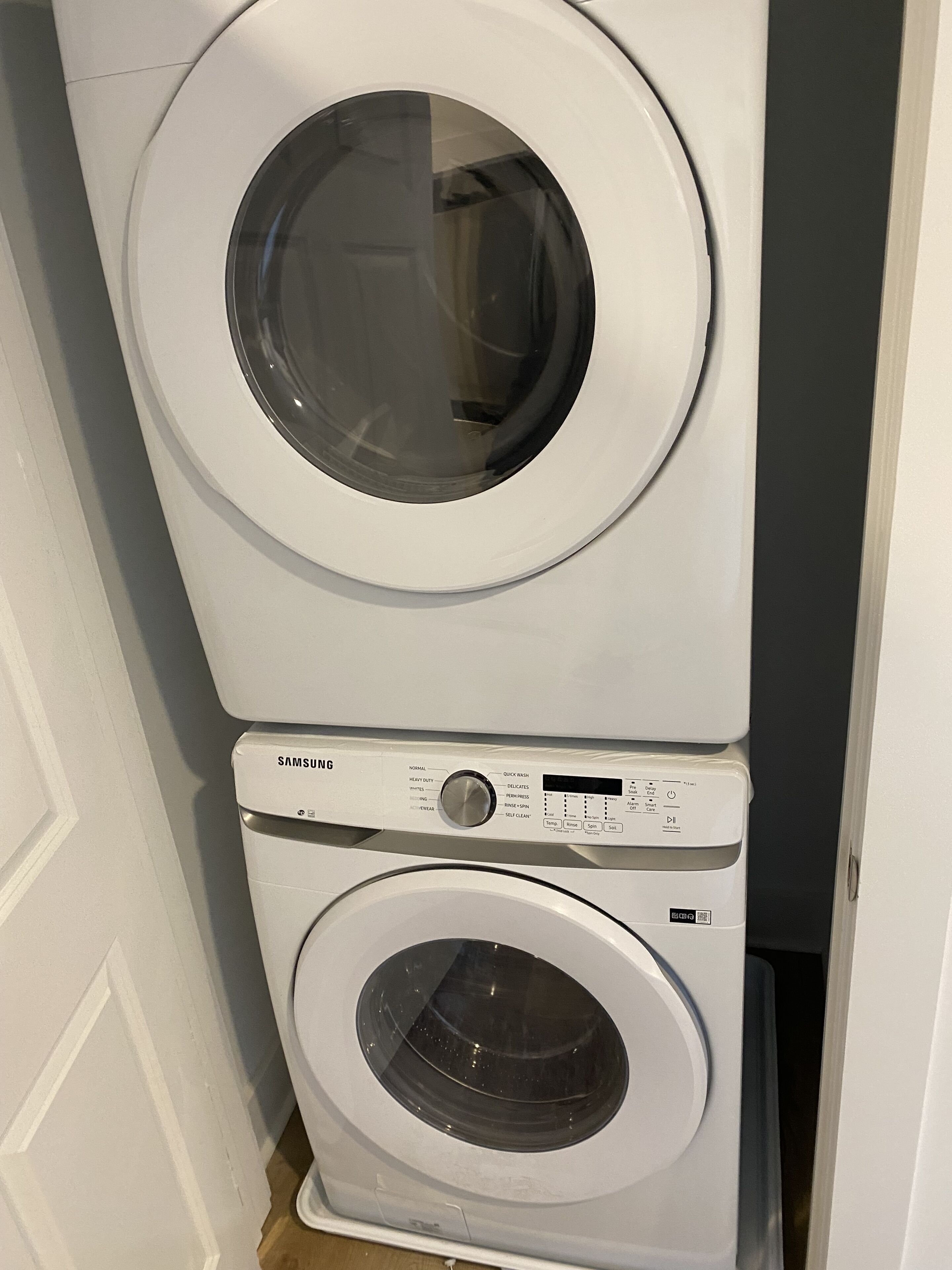 A stacked washer and dryer unit with control panels and labels.