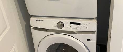 A stacked washer and dryer unit with control panels and labels.