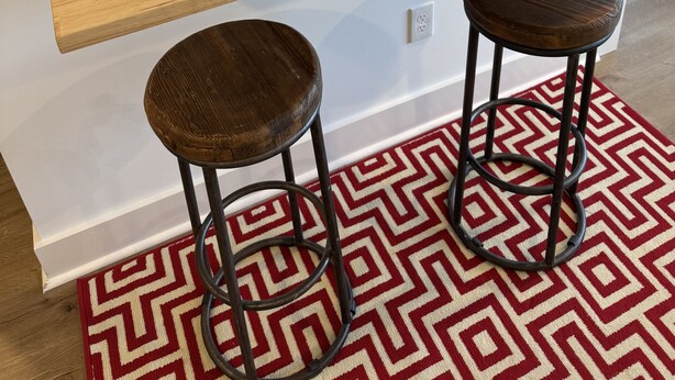 A kitchen with a wooden countertop, two stools, a patterned rug, and a mirror with a ship's wheel decoration. - Perfect beach Hideaway (Lewes)