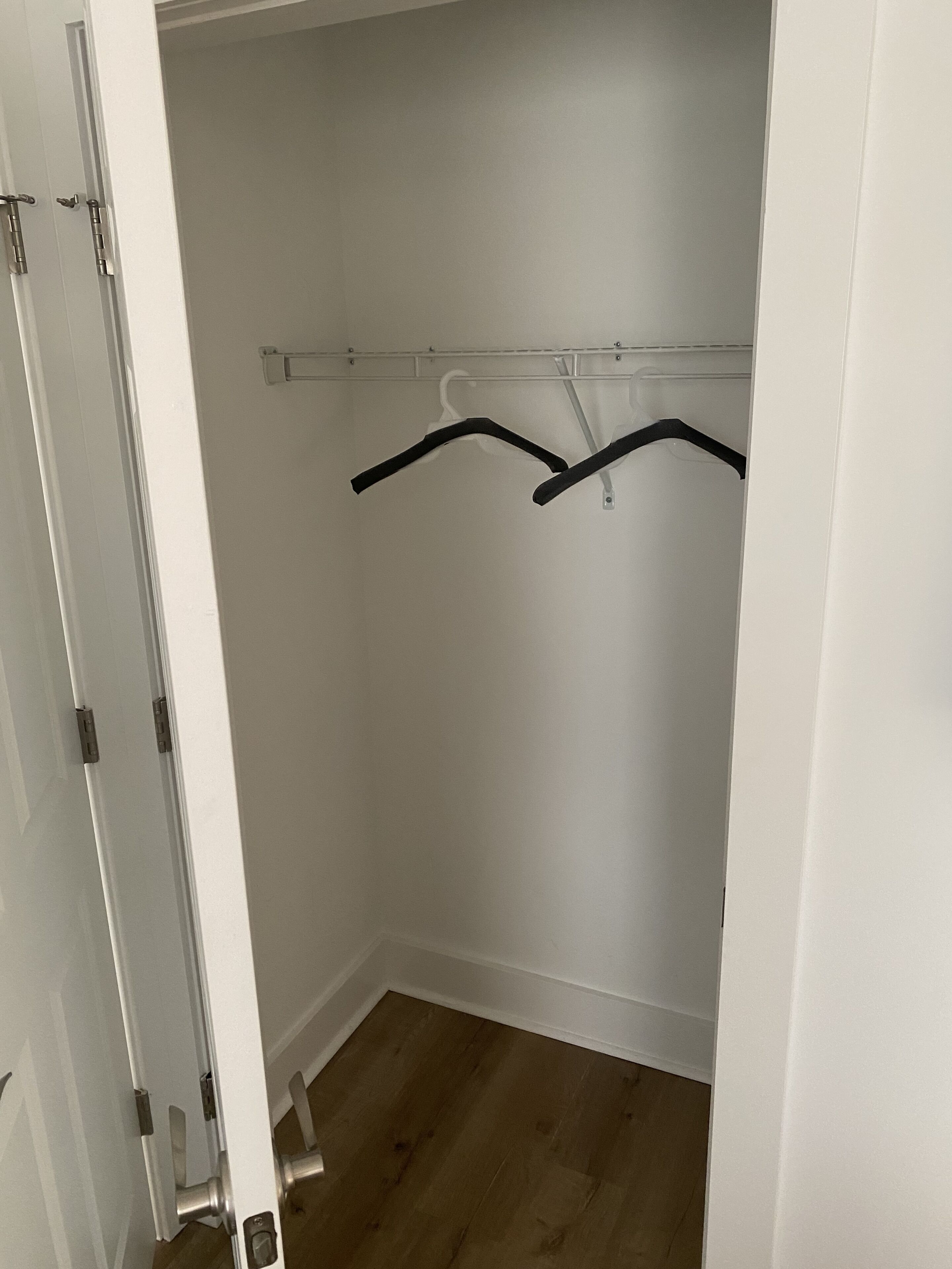 A walk-in closet with a wooden floor and a white wall.