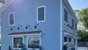 A two-story house with a covered porch, multiple windows, and outdoor lighting fixtures. - Perfect beach Hideaway (Lewes)
