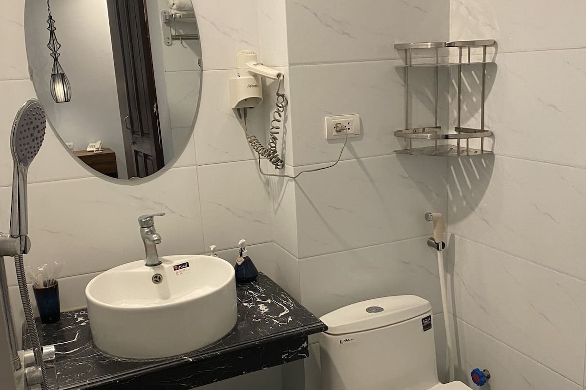 A bathroom with a white sink, toilet, and a mirror.