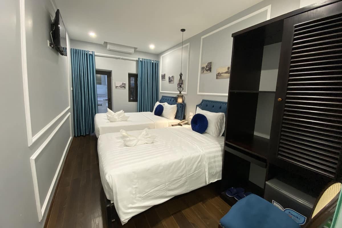 A hotel room with two beds, a wardrobe, a desk, and a chair.
