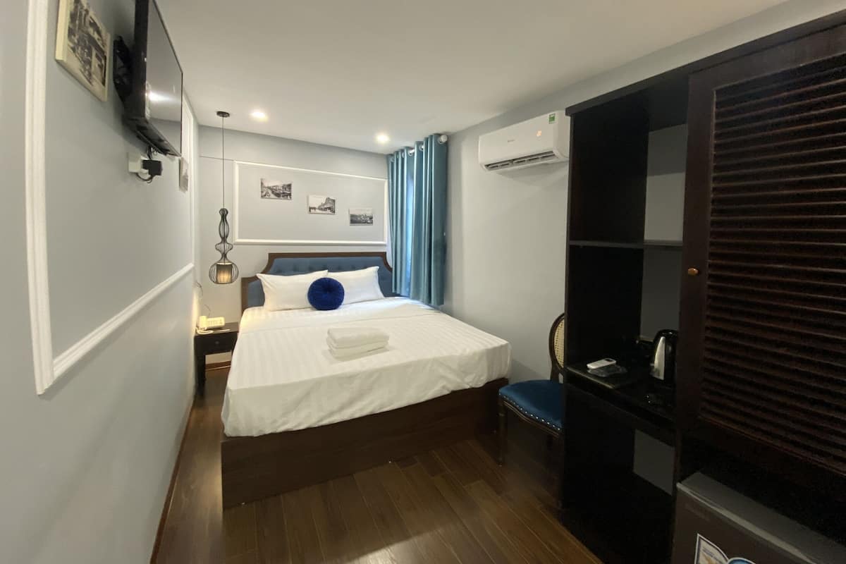 A hotel room with a bed, a chair, a desk, and a wardrobe.