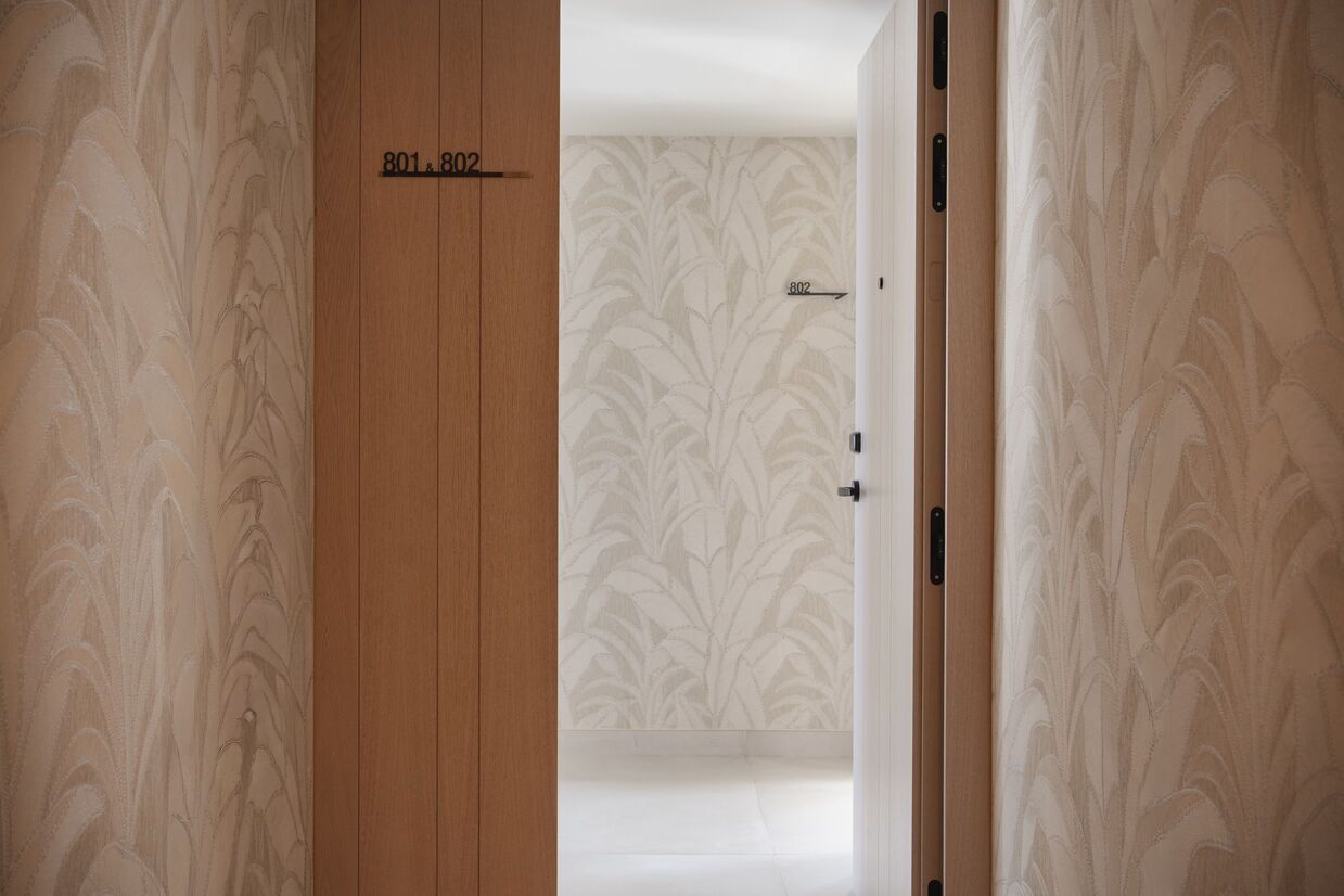 Une chambre d’hôtel avec une porte en bois portant l’inscription « 801.802 » et un papier peint à motifs.