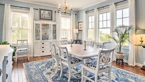 Une salle à manger avec une table en bois, des chaises blanches et un tapis à motifs bleus.