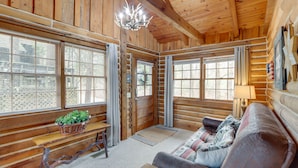 Ein Holzblockhaus-Interieur mit einer Holzbänkl, einem Sofa und einer Kandelaberleuchtre.