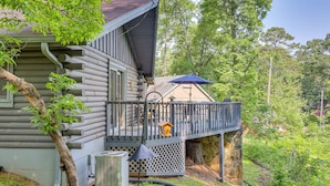 Eine Blockhütte mit Balkon, Vogelhaus und überdachter Sitzgelegenheit im Freien.