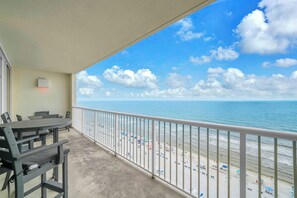 A balcony with a view of the beach and ocean.