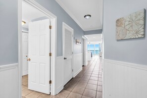 A hallway with white doors, a tiled floor, and a ceiling light.