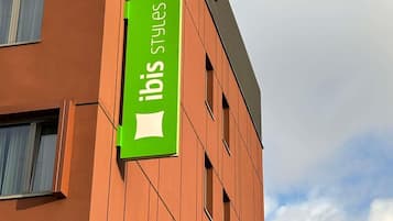 Um edifício com uma placa verde indicando 'ibis Styles'.