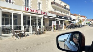 Une vue de rue avec un restaurant appelé « LE SAINT PAUL » et un bar situé de l’autre côté de la rue.