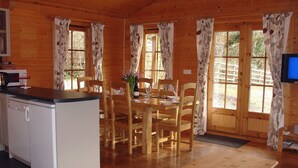 A wooden cabin with a kitchen, dining area, and a TV. - Valley Lodge (Tiverton)