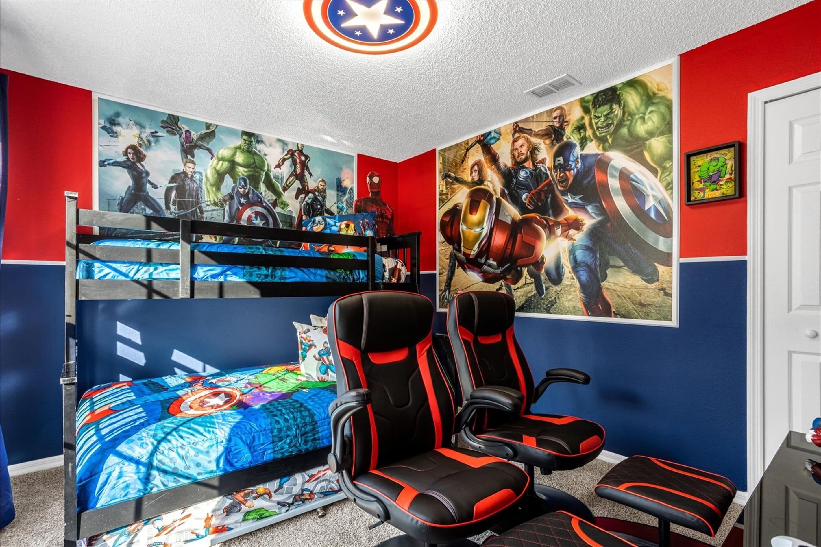 A child's bedroom with a bunk bed, gaming chair, and superhero-themed wall art.