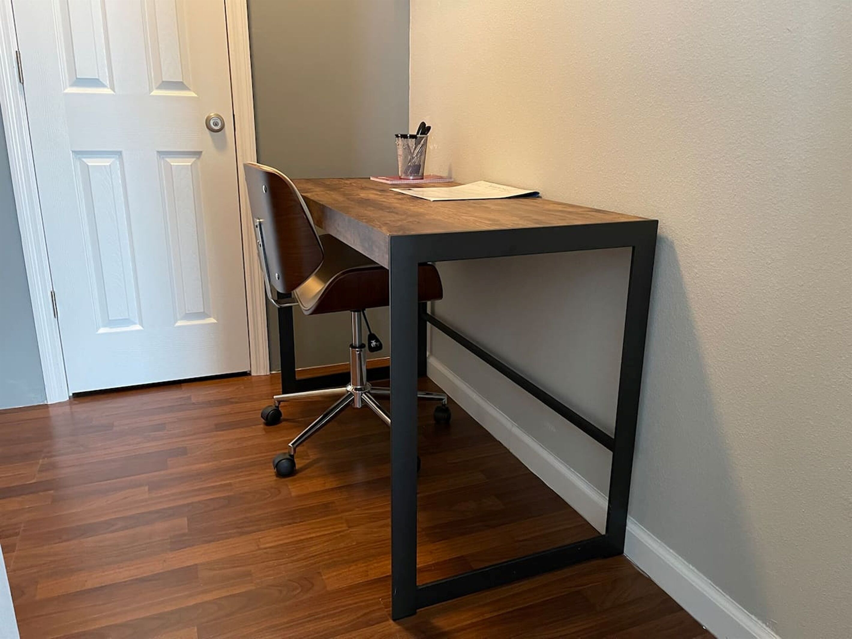 A corner desk with a chair, a door, and a wall.