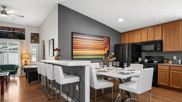 A modern kitchen with wooden cabinets, a black refrigerator, and a microwave. - Animatronic Dinosaur Villa: 3 King Rooms, Theater & Private Pool Near Disney (Clermont)