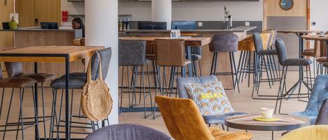 A modern cafe with multiple seating areas, including tables and chairs, and a bar counter.