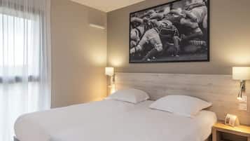 A hotel room with a large bed, two bedside lamps, a headboard, and a framed photograph on the wall.