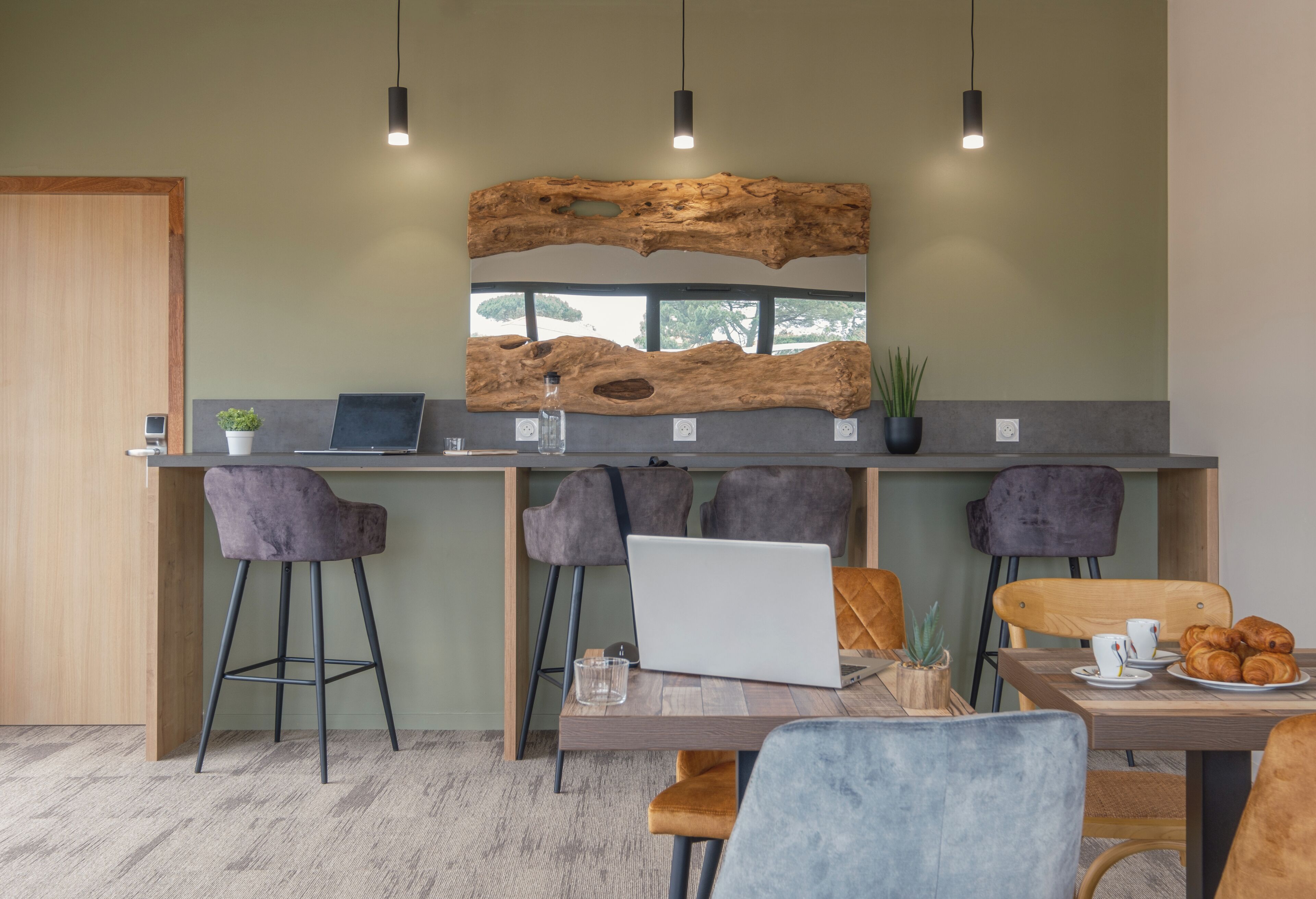 Une cuisine moderne avec des tabourets de bar, un mur d’accent en bois et un coin repas comprenant une table et des chaises.