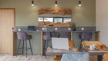 Une cuisine moderne avec des tabourets de bar, un mur d’accent en bois et un coin repas comprenant une table et des chaises.