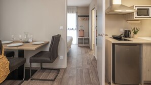 Een compacte hotelkamer met een zithoek, kitchenette en een bed op de achtergrond.