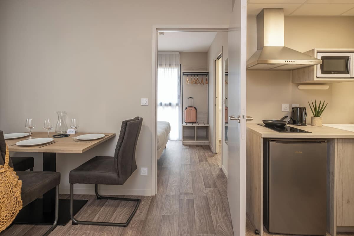 Une chambre d’hôtel compacte comprenant un coin repas, une kitchenette et un lit en arrière-plan.