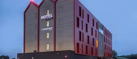 Un moderno edificio de hotel con un llamativo letrero que dice 'HOTEL', ventanas amplias y un techo plano.