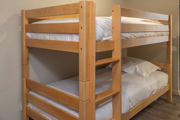A bunk bed with three levels, each with white bedding.
