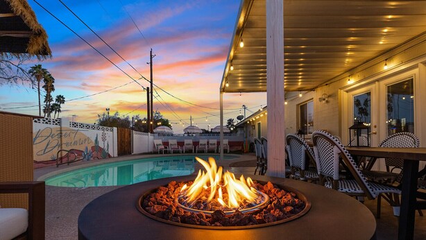 A poolside area with a fire pit, outdoor seating, and a view of the pool. - Heated Deep Diving Pool, Firepit, BeautyBar, Yard Games, 3 King + 2 Queen beds (Tempe)