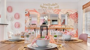 A dining area with a table set for two, featuring a floral wall mural and a sign that reads "scottsdale before the veil." - Heated Deep Diving Pool, Firepit, BeautyBar, Yard Games, 3 King + 2 Queen beds (Tempe)