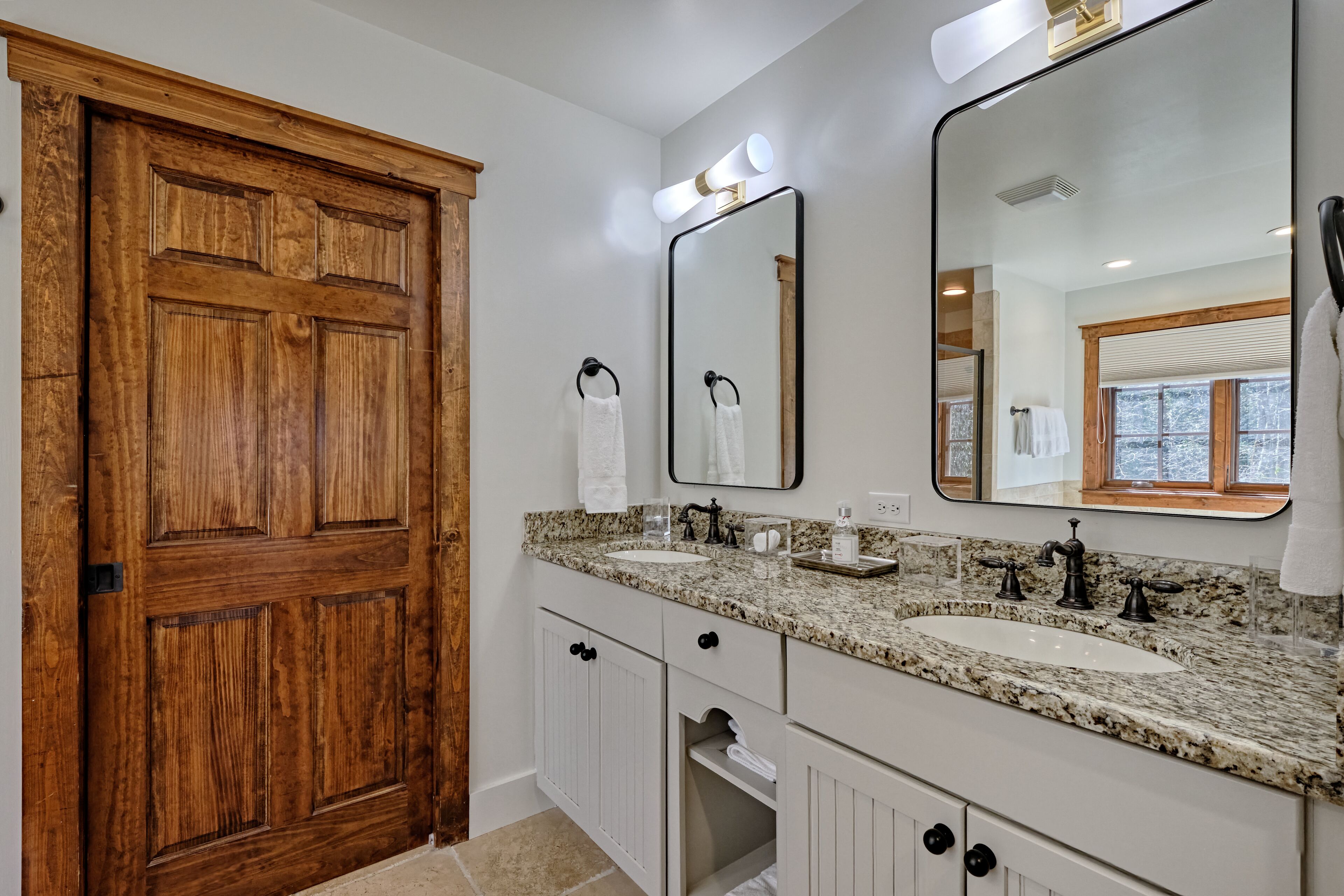 A bathroom with two sinks, a large mirror, and a wooden door.