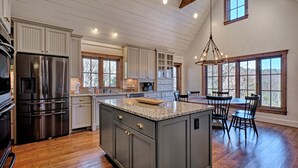 A spacious kitchen with a large island, stainless steel appliances, and ample natural light from large windows.