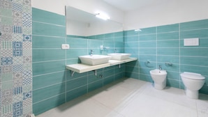 Et badeværelse med to håndvaske, en bidet og et toilet.