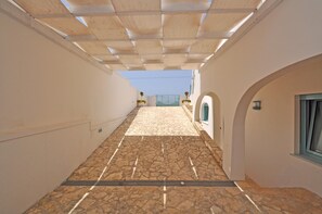 A narrow corridor with a tiled floor, a wooden ceiling, and a view of a gate in the distance. - Villa Esador by BarbarHouse (Torre Suda)