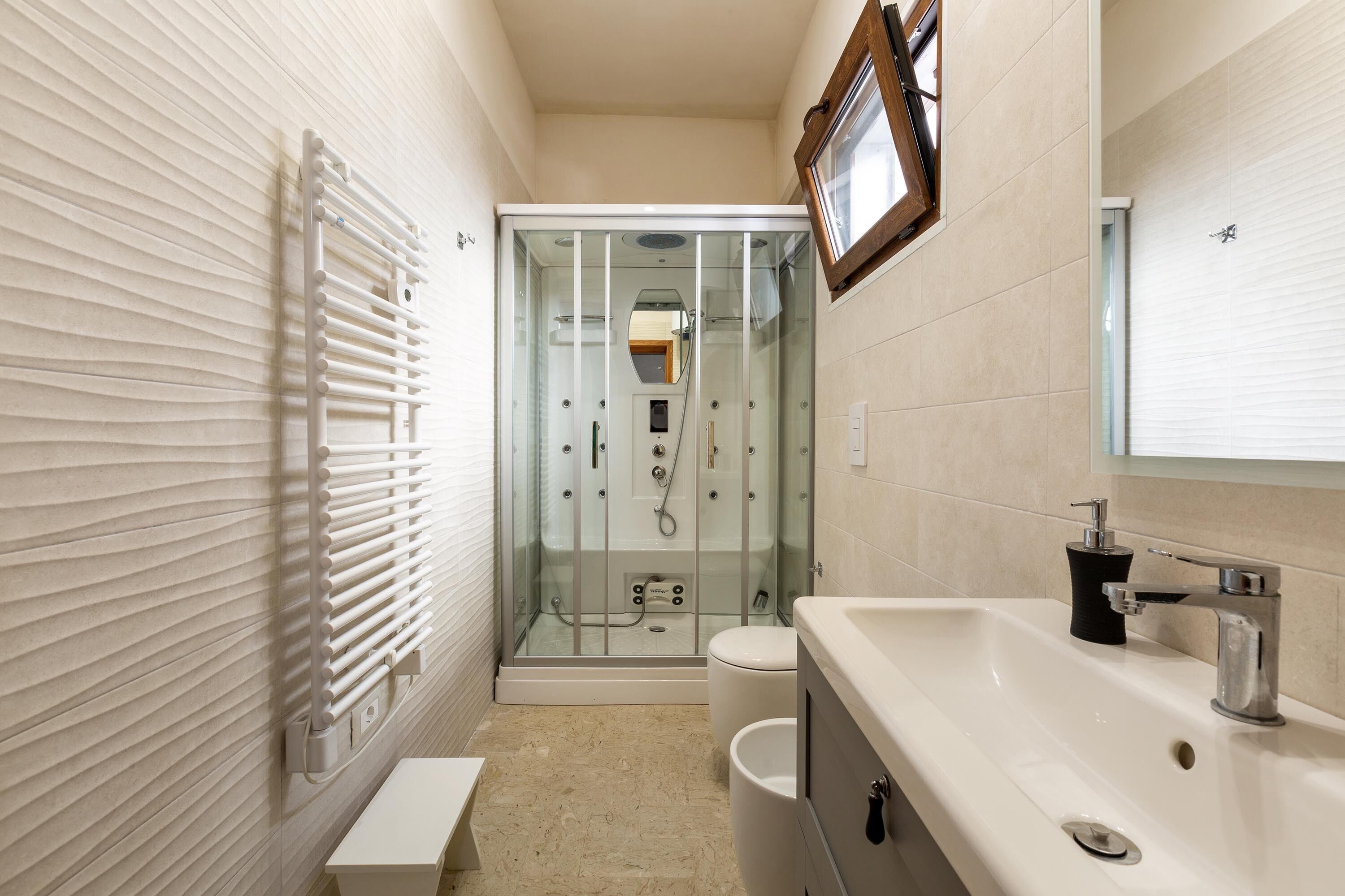 Un baño moderno con ducha de vidrio, un lavabo blanco y un inodoro.