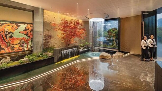 A lobby with a reflective marble floor, a waterfall feature, and a large mural. - Xiangli Hotel (Shawan Park Subway Station, Changsha High Speed Railway South Station) (Changsha)