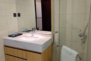 A modern bathroom with a white sink, a mirror, and a glass-enclosed shower. - Xiangli Hotel (Shawan Park Subway Station, Changsha High Speed Railway South Station) (Changsha)