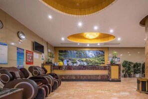 A hotel reception area with a reception desk, seating area with massage chairs, and a large wall mural. - Xiangli Hotel (Shawan Park Subway Station, Changsha High Speed Railway South Station) (Changsha)